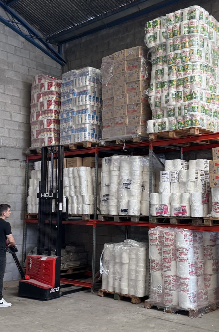 Operario moviendo pallets con un apilador eléctrico frente a los racks de un depósito
